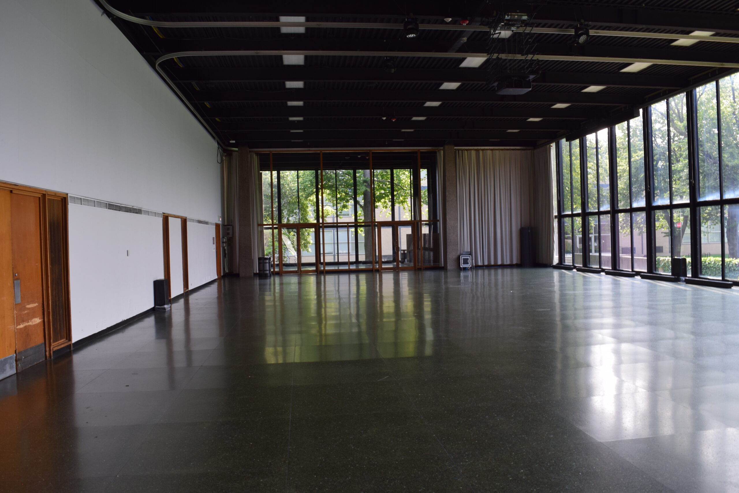 A large empty room with large windows letting in sunlight from the right side.