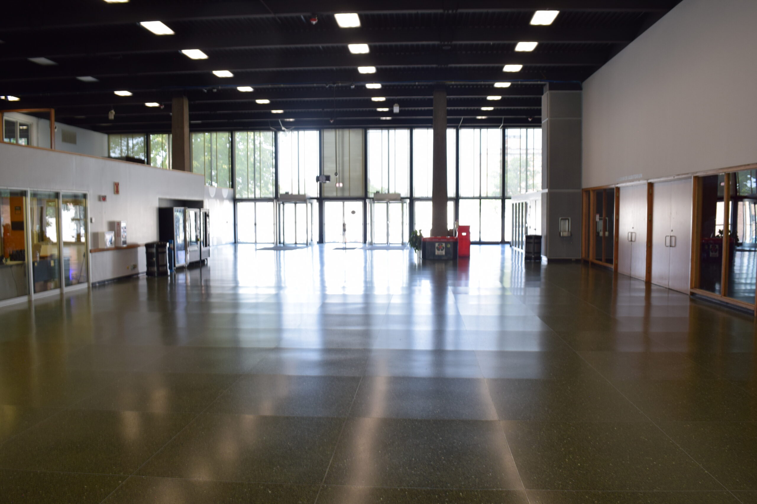 <br />
A large open area in Hermann Hall, facing west, with revolving and pull doors at the end, and the auditorium entrance on the right.