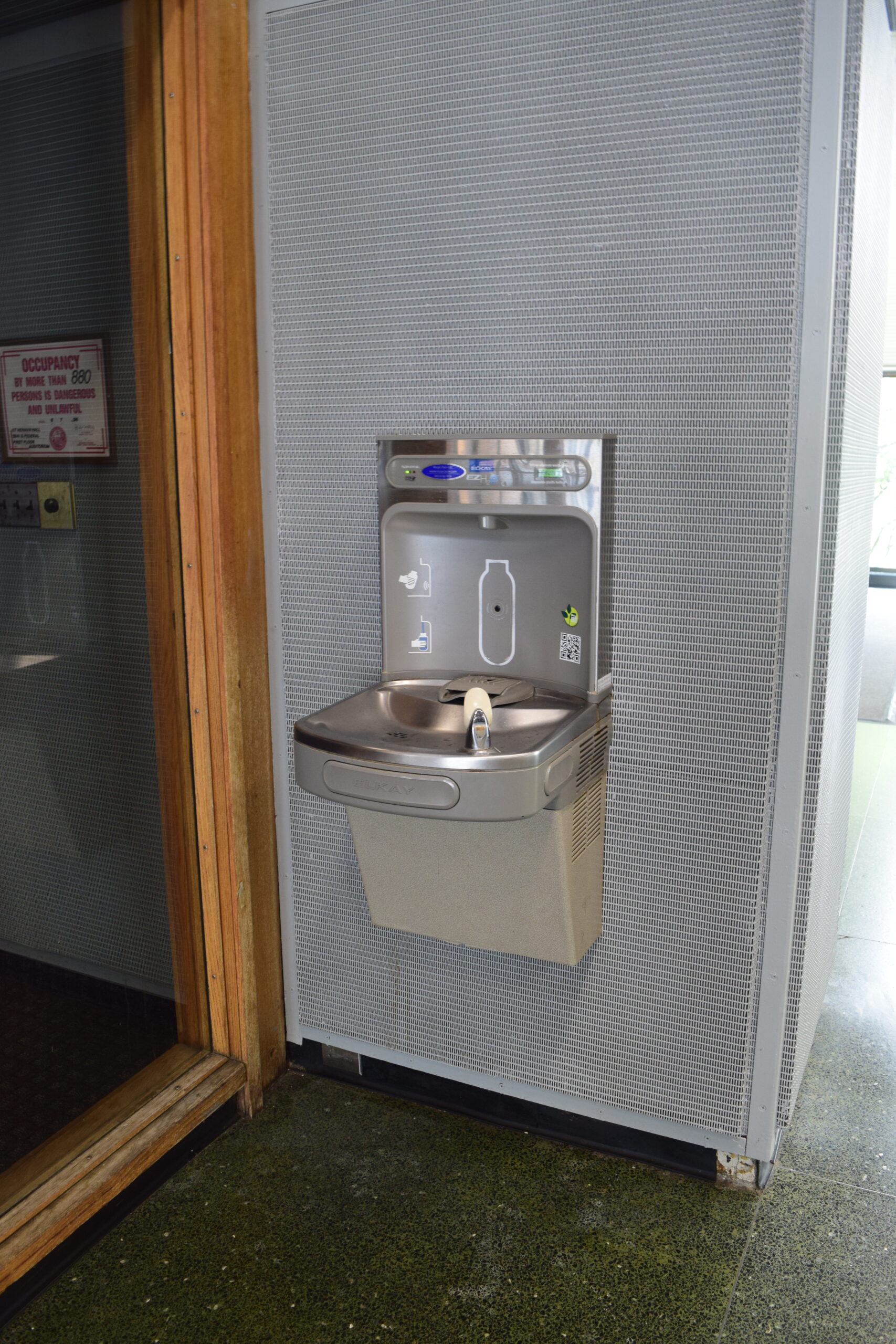 A water fountain, low to the ground with a spout for drinking and a tap at the back to fill water bottles.